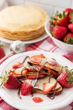 some strawberries and pancakes on a white plate