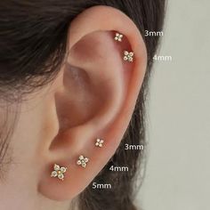 three small white flowers are attached to the side of a woman's right ear