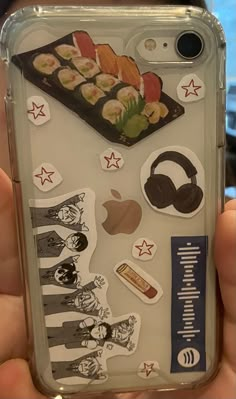 someone is holding their phone case with sushi stickers on it and headphones