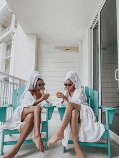 two women sitting on blue chairs with towels wrapped around their heads and holding drinks in their hands