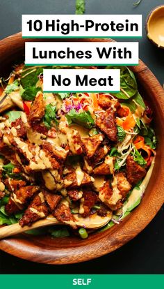 a wooden bowl filled with meat and vegetables on top of a black table next to a spoon