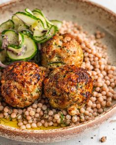 three meatballs and beans in a bowl with cucumbers on the side for garnish