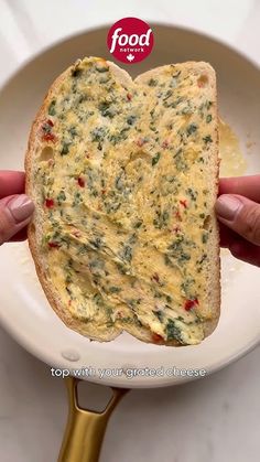 a person holding up a piece of bread on a plate with a spoon in it