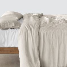 an unmade bed with white sheets and pillows