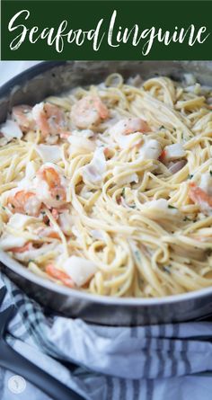 a pan filled with pasta and shrimp on top of a table next to a fork