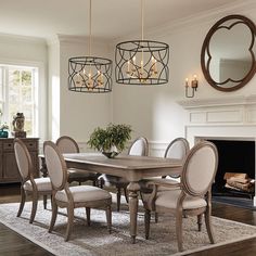 a dining room table with six chairs and a chandelier above it in front of a fireplace