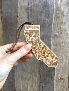 a hand holding an ornament that looks like the state of california in wood