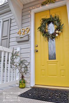 a yellow front door with a wreath on it