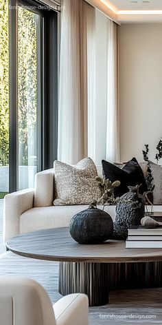 a living room filled with lots of furniture next to a large glass window and white walls