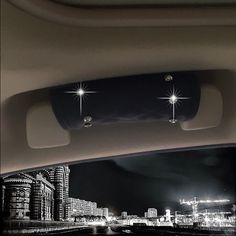 the interior of a car with city lights and buildings in the background at night time