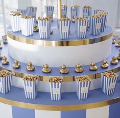 a three tiered cake with blue and white striped frosting topped with gold popcorn