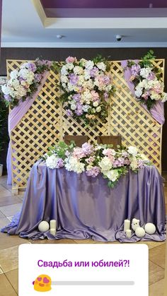 the table is covered with purple cloth and white flowers, which are arranged on top of each other