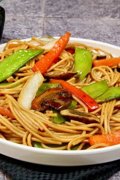 a white bowl filled with noodles and vegetables