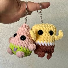 two crocheted keychains are being held by someone