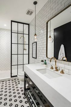 a bathroom with black and white tiles, gold fixtures and a large mirror on the wall