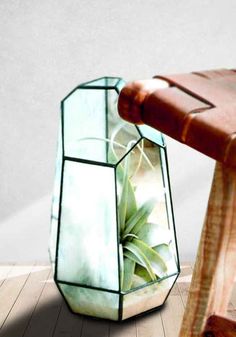 a wooden bench sitting on top of a hard wood floor next to a glass vase