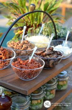 several bowls of food are on a table with jars and spoons next to them