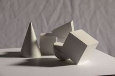 three white sculptures sitting on top of a table next to each other and one is made out of paper