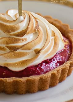 a dessert with whipped cream on top and a cherry pie in the middle, sitting on a white plate