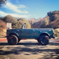 an old pick up truck is parked on the side of the road with trees in the background