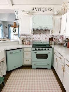 an old fashioned kitchen with white cabinets and pink checkered rugs on the floor