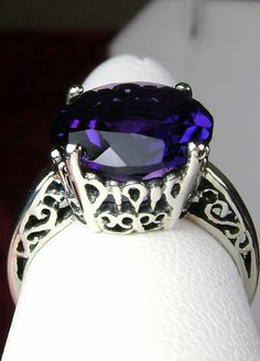 "Simulated Amethyst Ring K Ring Design#4 Custom Made This is a brand new Victorian design in solid sterling silver. The beautiful trellis filigree of the ring is amazing vintage style. This full cut sparkling gemstone is 13mm ( approximately 1/2\") in diameter. The inside of the band is marked 925 for sterling silver. It is a ring that will be treasured as an heirloom. Notice the beautifully intricate design of the silver filigree setting and trellis band. This alluring ring has beautiful shine Oval Purple Filigree Amethyst Ring, Oval Purple Amethyst Ring With Filigree, Oval Amethyst Ring With Intricate Design, Purple Oval Amethyst Ring With Filigree, Purple Amethyst Ring With Filigree, Purple Oval Filigree Ring As A Gift, Oval Purple Filigree Ring As Gift, Purple Oval Filigree Ring For Gift, Ornate Round Purple Amethyst Ring