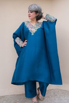 Blue kaftan with resham, zardozi applique embroidered V neck and sleeve cuffs. Paired with printed straight fit pant.
Components: 2
Pattern: Applique Embroidered
Type Of Work: Resham and Zardozi Work
Neckline: V Neck
Sleeve Type: Batwing Sleeves
Fabric: Pure Silk
Color: Blue
Other Details: 
Cut work hem details
Asymmetric hem on kaftan
Note: The outfit worn by the other model on the left is not for sale
Occasion: Mehendi and Haldi,Sangeet - Aza Fashions Blue Abaya With Dabka Work For Wedding, Anarkali Kaftan With Long Sleeves And Dabka Work, Blue Wedding Abaya With Dabka Work, Blue Bohemian Thobe For Wedding, Blue Festive Thobe For Eid, Traditional Blue Abaya With Dabka, Traditional Blue Thobe For Eid, Festive Blue Thobe With Dabka Work, Anarkali Kaftan For Eid In Blue