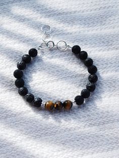 This Tigers Eye and Lava bracelet is sure to become an everyday staple. Tigers eye promotes inner strength and was once considered more precious than gold. Part of our Men's Collection, but designed to be gender inclusive, this unique bracelet is a classic staple.✦ DETAILS ✦✧ Name: Ekewaka (eh-keh-WAH-kah) - The protector or guardian of riches or wealth.✧ Genuine Tigers Eye beads .✧ 8mm Lava Beads.✧ Sterling silver components.✧ All Ke Aloha Jewelry pieces come packaged thoughtfully, beautifully, 8mm Beads Bracelet For Meditation, Everyday Spiritual Bangle Bracelet, Symbolic Hand-strung Bracelet Jewelry, Symbolic Hand-strung Jewelry Bracelet, Meditation Bracelets With Natural Lava Stones, Spiritual Bracelets With Round Beads For Everyday, Spiritual Round Bead Bracelets For Everyday, Minimalist Bracelets With 8mm Beads For Healing, Spiritual 8mm Beads Jewelry For Everyday