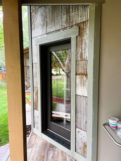 an open window on the side of a house with grass in the backround