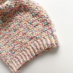 a close up of a knitted sweater on a white surface with the fabric pulled back