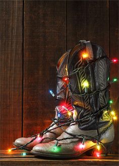 a pair of boots with christmas lights on them sitting in front of a wooden wall