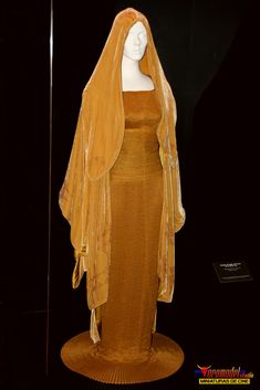 a mannequin dressed in an orange dress with a veil on it's head