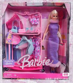 a barbie doll in a pink and purple dress with clothes on a shelf next to it