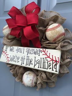 a wreath with baseballs and a bow hanging on the front door for someone to welcome