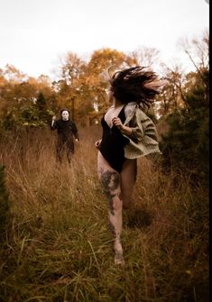 a woman running through a field next to a creepy man