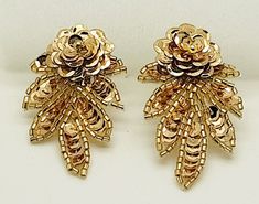 Add a touch of vintage glamour to any occasion with these beautiful handmade clip-on earrings. The gold seed beaded and sequined flower design hangs elegantly from the lobe, measuring 2.5 inches in length. The chandelier style earrings are perfect for dressing up any outfit, and are ideal for events such as weddings, anniversaries, and graduations. These earrings are a timeless piece of beauty, with a bohemian and retro feel. The intricate beading is crafted from glass seed beads and sequins, and the earrings are made from an alloy metal. They are a unique and special gift idea for any special occasion, such as Mother's Day, Father's Day, birthdays, and Valentine's Day. * gold *2.5" length x 1.5" (w) * Clip-on * Hand beaded * light weight Intricate Beading, Chandelier Style, Handmade Gold, Vintage Glamour, Style Earrings, Hand Beading, Vintage Watches, Flower Design, Special Gift