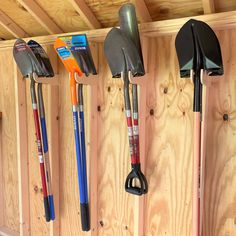 there are many different types of shovels hanging on the wall