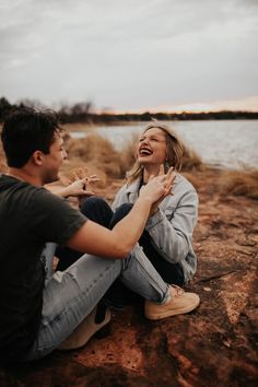 a man and woman sitting on the ground laughing