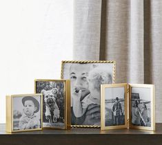 four gold frames with photos on them sitting on a table next to a curtain and window