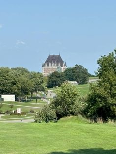 a large building sitting on top of a lush green field next to a tree filled park