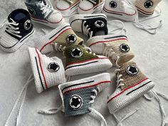 several crocheted sneakers are arranged on a white surface with black and red accents