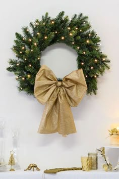 a christmas wreath is hung on the wall next to a table with candles and other decorations