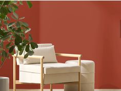 a white chair sitting next to a potted plant in a room with red walls