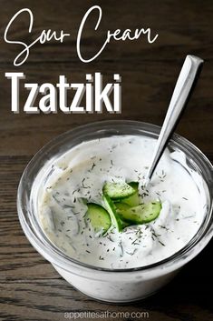 a bowl filled with cucumber and cream on top of a wooden table next to a