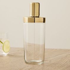 a clear glass with a gold lid next to a lime