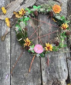 a wreath made out of flowers and twigs on a wooden surface with leaves around it