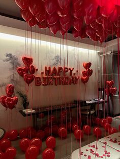 red balloons are hanging from the ceiling in front of a happy birthday sign