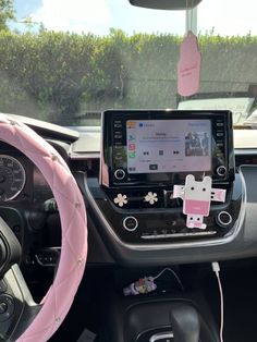 the interior of a car with an electronic device in the center and pink steering wheel