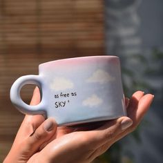 a hand holding a coffee mug with writing on it that says so free as sky