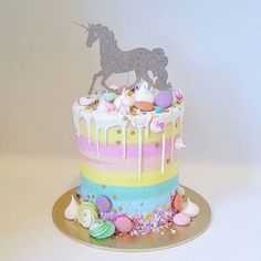 there is a cake decorated with unicorns and candy on the top, as well as confetti